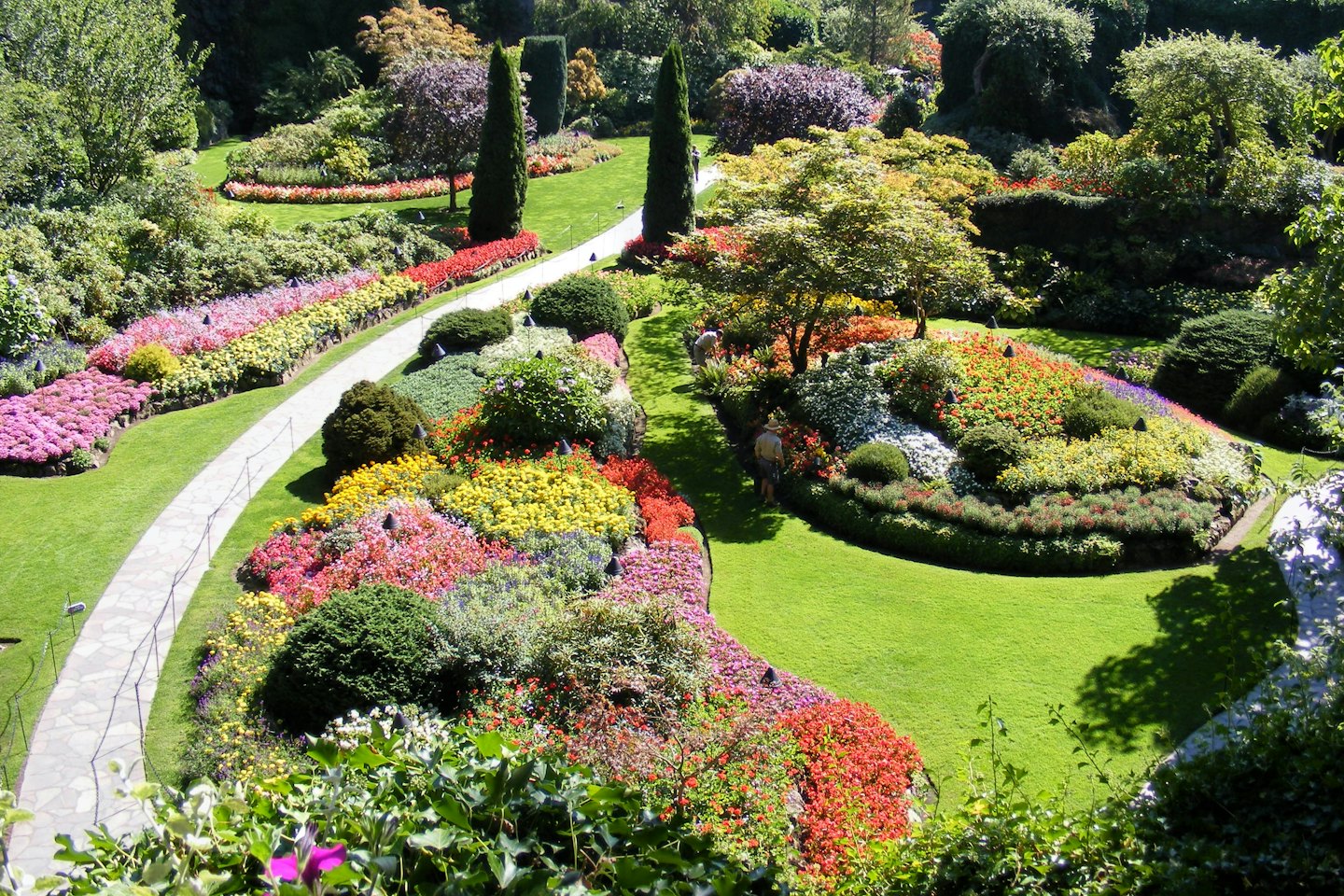 Sentieri di pietra si snodano tra aiuole fiorite in un giardino botanico.