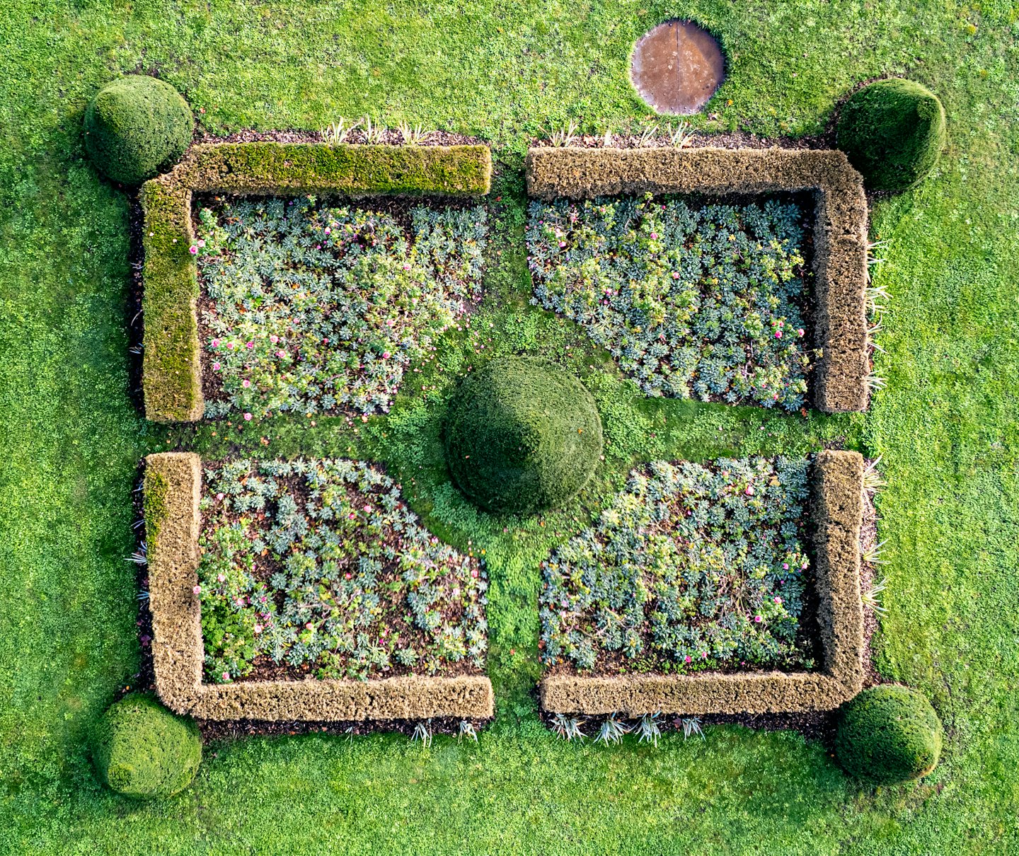 Giardini formali con fogliame verde e fiori rosa dall'alto.