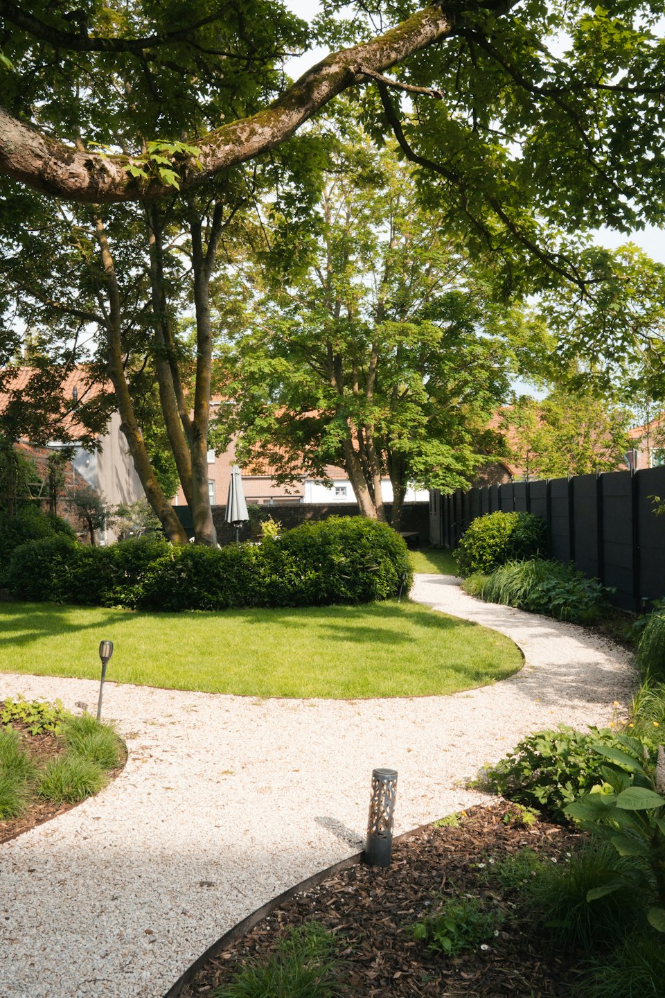 Un sentiero di ghiaia serpeggia attraverso un giardino curato con siepi.